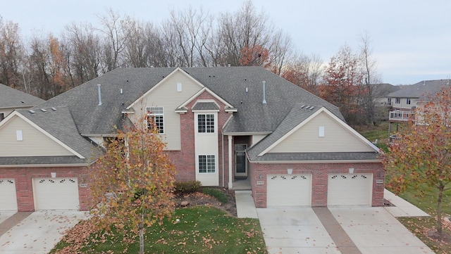 traditional-style home featuring driveway, brick siding, roof with shingles, and an attached garage