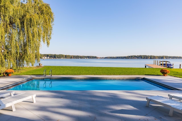 pool with a patio area, a lawn, and a water view