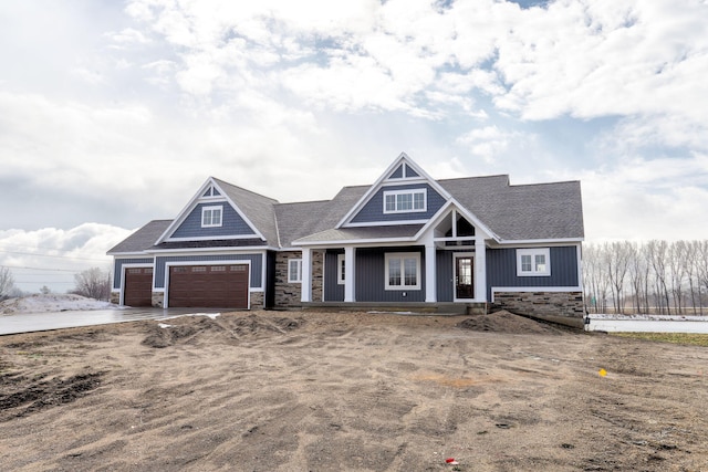 craftsman house with covered porch, stone siding, and an attached garage