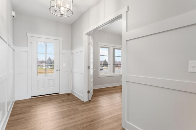 entrance foyer featuring a wealth of natural light, a notable chandelier, a decorative wall, and wood finished floors