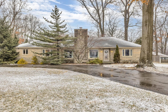 single story home with stone siding and a chimney