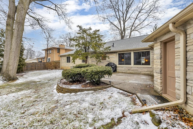 yard covered in snow with a patio area and fence