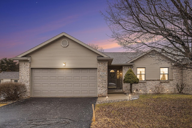 ranch-style home with driveway, an attached garage, a shingled roof, and brick siding