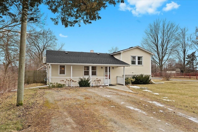 tri-level home featuring a porch, fence, roof with shingles, a front lawn, and a chimney