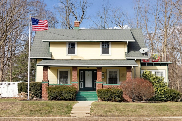 view of front of house with brick siding, a chimney, a porch, a front yard, and fence