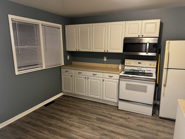 kitchen with white appliances, white cabinetry, baseboards, and dark wood finished floors