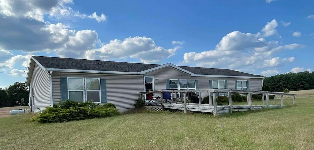 rear view of house featuring a lawn and a wooden deck