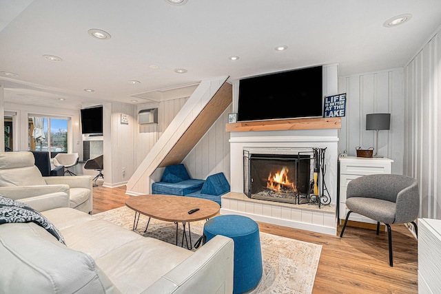 living room featuring recessed lighting, a fireplace, stairs, and light wood-type flooring