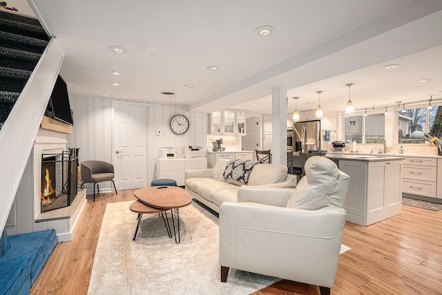 living room featuring light wood-style flooring, recessed lighting, and a lit fireplace