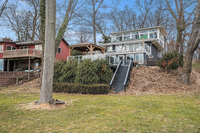 back of property featuring a gazebo, stone siding, a lawn, and stairs