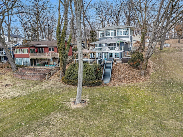 back of house featuring stairs, a deck, a lawn, and a residential view