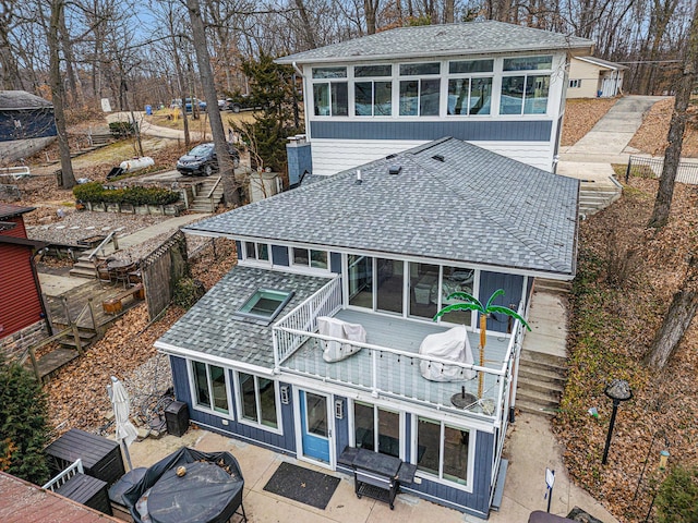 back of house featuring a patio area, roof with shingles, and a sunroom