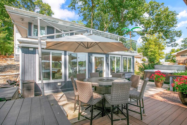 deck featuring outdoor dining area and a hot tub