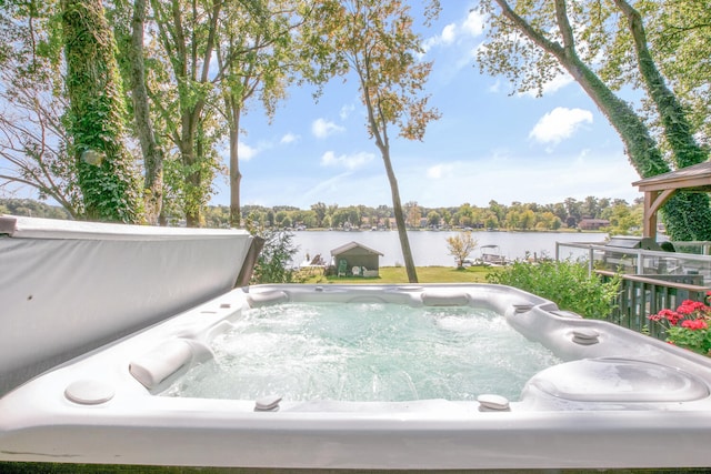 view of pool with a hot tub and a water view