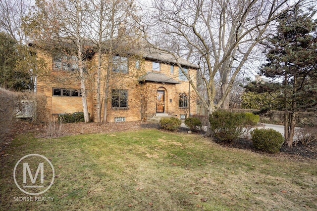 view of front of property featuring brick siding, a front lawn, and a chimney