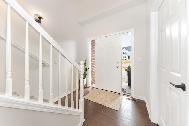 foyer featuring dark wood-style flooring, stairway, and visible vents