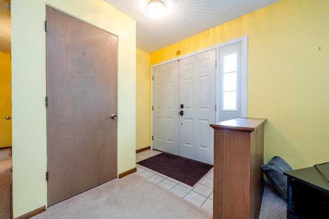 carpeted entryway with a textured ceiling, tile patterned flooring, and baseboards