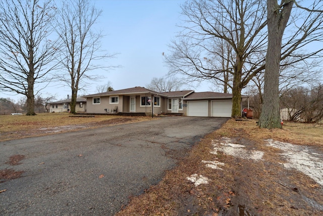 ranch-style house with aphalt driveway and an attached garage