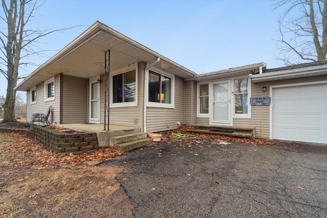 ranch-style home with an attached garage and aphalt driveway