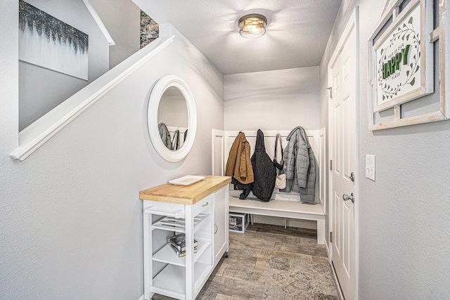 mudroom with a textured wall and stone finish flooring