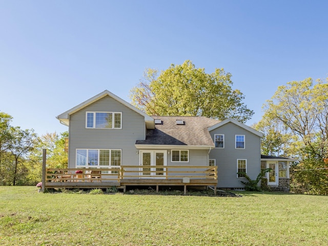 back of house with roof with shingles, a lawn, and a wooden deck