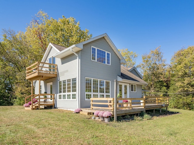 back of house with roof with shingles, a lawn, a balcony, and a wooden deck