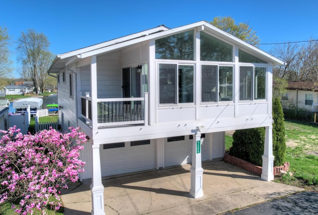 exterior space with a garage, a sunroom, and concrete driveway