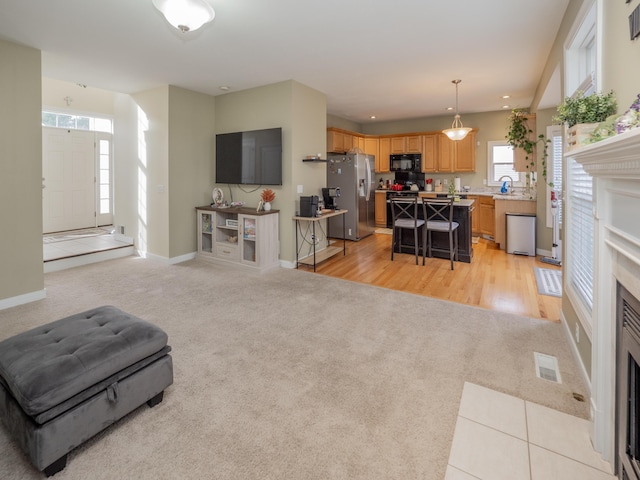 living room with recessed lighting, light colored carpet, visible vents, a fireplace with flush hearth, and baseboards