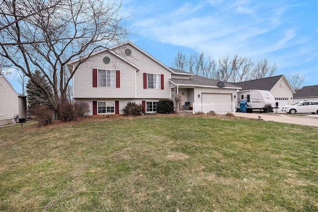 split level home with concrete driveway, a front lawn, and an attached garage