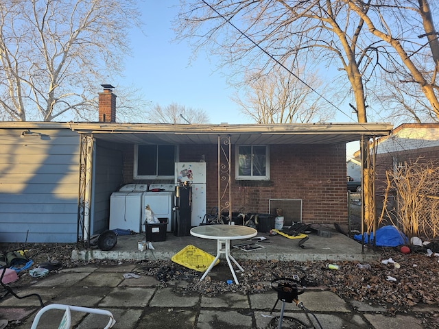 rear view of house featuring a patio, brick siding, a chimney, and washing machine and clothes dryer