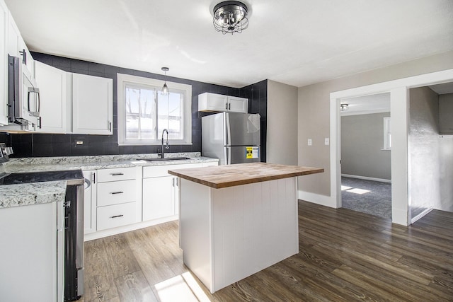 kitchen with white cabinets, dark wood-style floors, wood counters, stainless steel appliances, and a sink