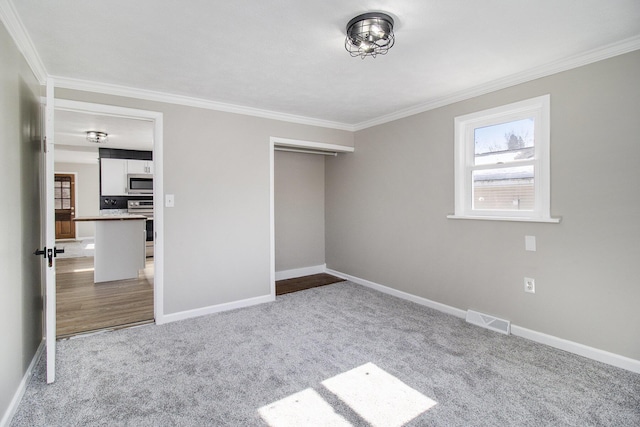 unfurnished bedroom with ornamental molding, carpet flooring, visible vents, and baseboards