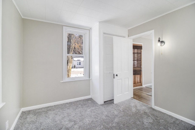 unfurnished bedroom featuring baseboards, multiple windows, carpet, and crown molding