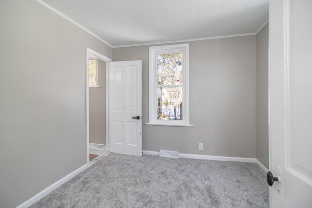 carpeted empty room featuring crown molding, visible vents, and baseboards