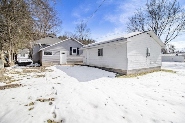 snow covered rear of property with an outdoor structure