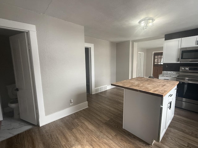 kitchen with stainless steel appliances, dark wood-style flooring, visible vents, white cabinetry, and wooden counters