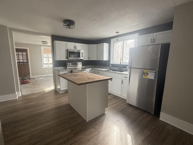 kitchen with dark wood-style floors, a center island, stainless steel appliances, wooden counters, and a sink