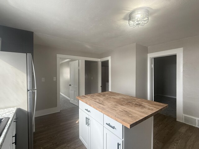 kitchen featuring butcher block counters, dark wood-type flooring, freestanding refrigerator, and white cabinets