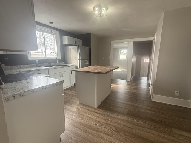 kitchen featuring a wealth of natural light, butcher block counters, dark wood-type flooring, freestanding refrigerator, and a sink