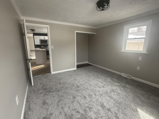 unfurnished bedroom featuring baseboards, crown molding, visible vents, and carpet flooring