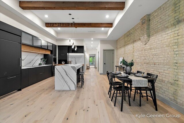 52 E 8th St Ste 210, Holland, MI 49423 - kitchen with modern cabinets, dark cabinetry, brick wall, beam ceiling, and pendant lighting