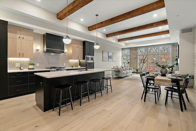 kitchen featuring light countertops, premium range hood, a breakfast bar, decorative backsplash, and light wood-style flooring