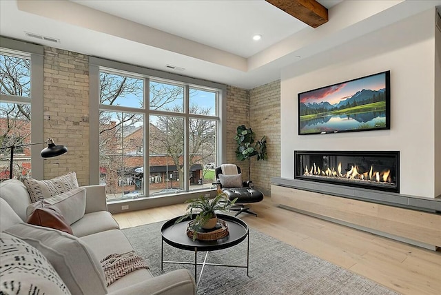 living area with wood finished floors, a healthy amount of sunlight, and a glass covered fireplace