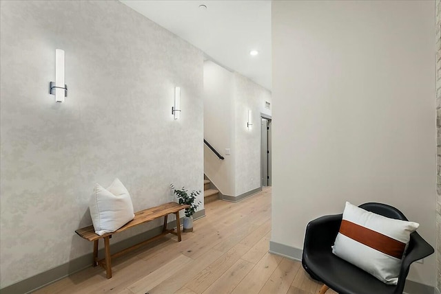 corridor with light wood finished floors, baseboards, recessed lighting, and stairway