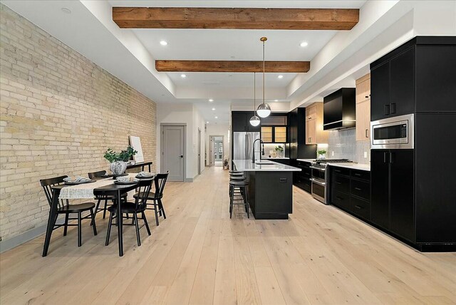 kitchen with a breakfast bar area, light countertops, dark cabinets, and stainless steel appliances