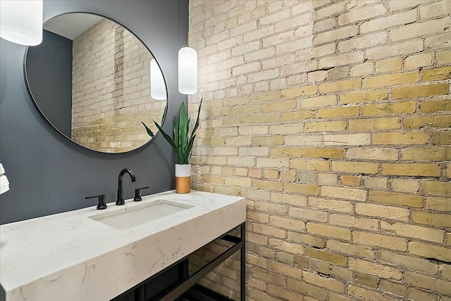 bathroom featuring vanity and brick wall