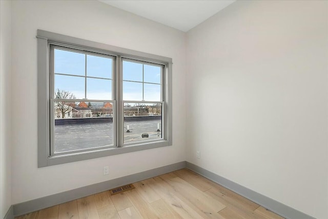 empty room featuring baseboards, visible vents, and light wood-type flooring