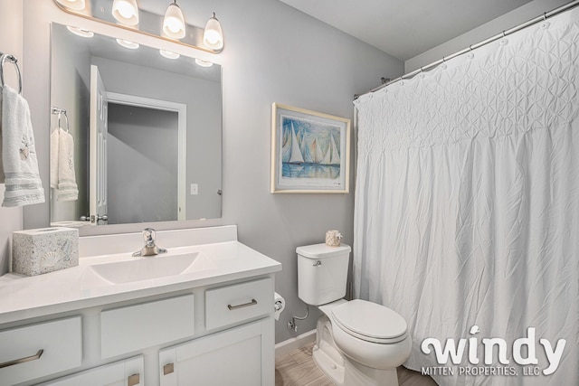 bathroom featuring baseboards, vanity, and toilet