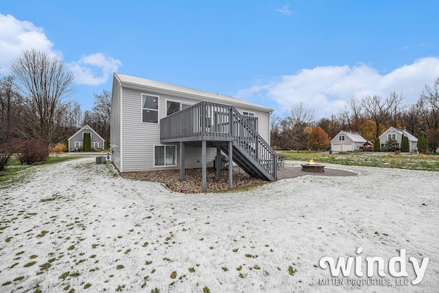 rear view of house featuring central air condition unit, a fire pit, a wooden deck, and stairs