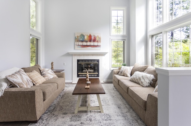 living area featuring a towering ceiling, baseboards, and a tile fireplace